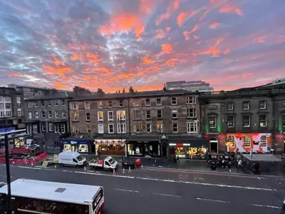 a city street with a bus in front of buildings at Spacious modern city centre apartment Castle Views in Edinburgh