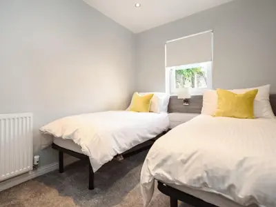 two beds in a bedroom with white walls and yellow pillows at The White House in Callander