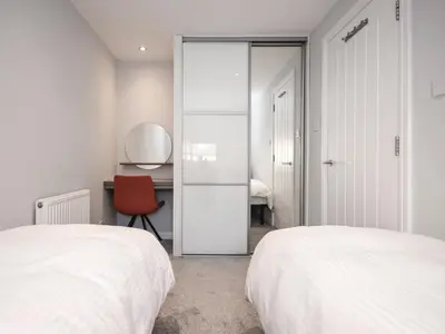 a bedroom with two beds and a desk and a red chair at The White House in Callander
