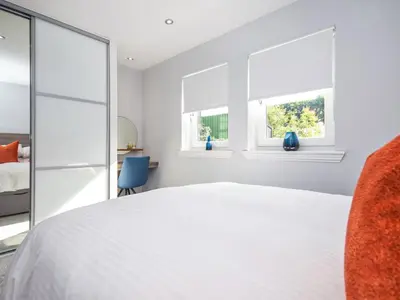 a bedroom with a white bed and two windows at The White House in Callander