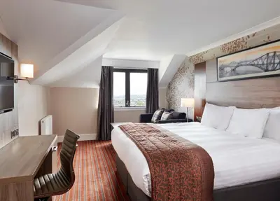 a hotel room with a large bed and a desk at Leonardo Edinburgh Murrayfield in Edinburgh