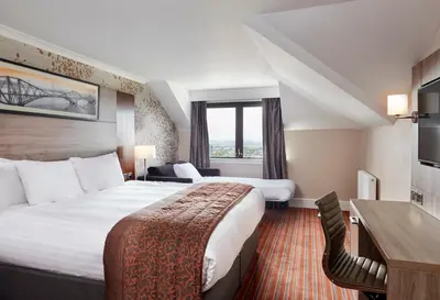 a hotel room with two beds and a desk at Leonardo Edinburgh Murrayfield in Edinburgh