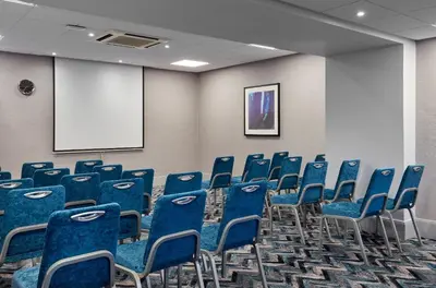 a conference room with blue chairs and a screen at Leonardo Edinburgh Murrayfield in Edinburgh