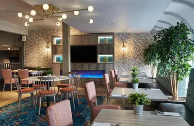 a restaurant with tables and chairs and a flat screen tv at Leonardo Edinburgh Murrayfield in Edinburgh