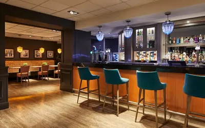 a bar with blue chairs in a restaurant at Leonardo Edinburgh Murrayfield in Edinburgh