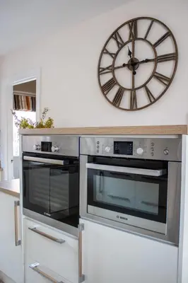 a clock on a wall above a kitchen oven at Harvest House with Games Room in Stirling