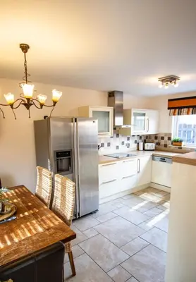 a kitchen with a table and a stainless steel refrigerator at Harvest House with Games Room in Stirling