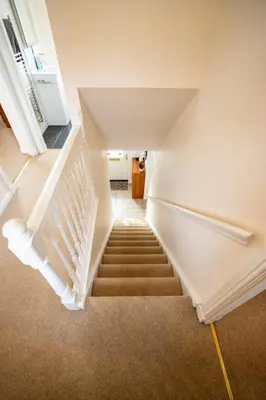 a staircase in a house with white walls and carpet at Harvest House with Games Room in Stirling
