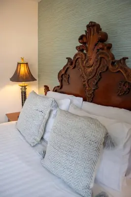 a bed with a wooden headboard and white pillows at Harvest House with Games Room in Stirling