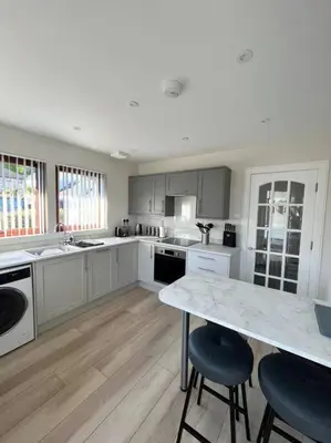 a kitchen with white cabinets and a marble counter top at Cragside in Callander