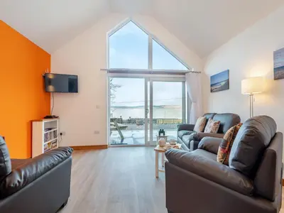 a living room with two couches and a large window at Postbox Cottage in Lochranza
