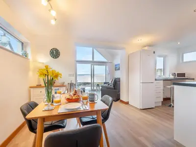 a kitchen and living room with a table and chairs at Postbox Cottage in Lochranza