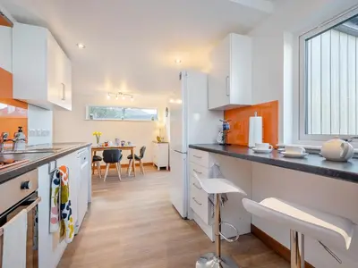 a kitchen with white cabinets and a large window at Postbox Cottage in Lochranza