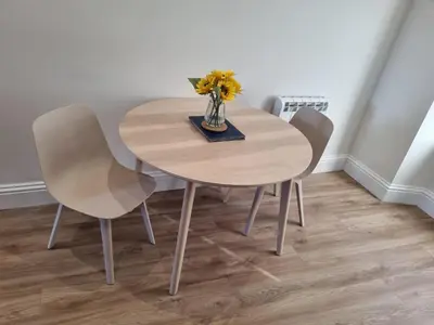 a wooden table with two chairs and a vase with flowers at The Rail & Ferry Den in Oban