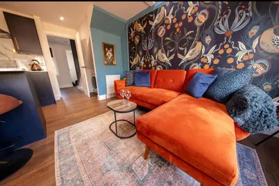 a living room with an orange couch and a table at The Bradan - Troon - Coorie Doon Stays in Troon