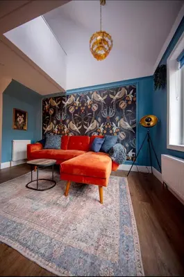 a living room with a red couch and a rug at The Bradan - Troon - Coorie Doon Stays in Troon