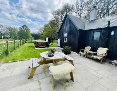 a patio with a table and chairs and a building at 2 bed lodge with private hot tub in Aviemore in Saint Ninians