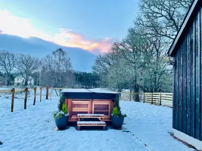 a shed with a picnic table in the snow at 2 bed lodge with private hot tub in Aviemore in Saint Ninians