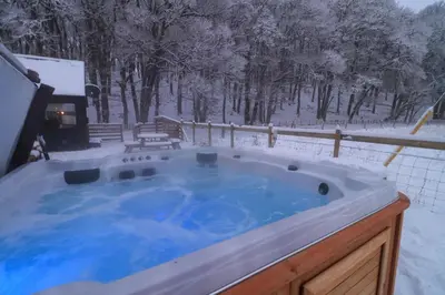 a jacuzzi tub in a snow covered yard at 2 bed lodge with private hot tub in Aviemore in Saint Ninians
