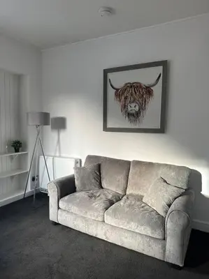 a couch in a living room with a picture of a bull at Combie Lane Apartments in Oban