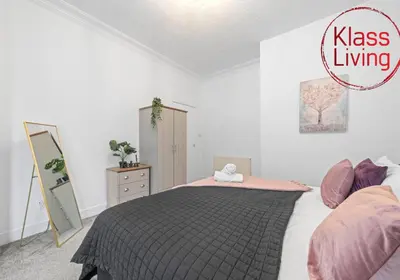 a bedroom with a bed with a black and pink blanket at Bute Apartment by Klass Living Coatbridge in Coatbridge