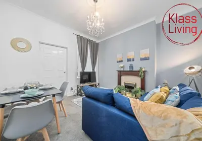 a living room with a blue couch and a table at Bute Apartment by Klass Living Coatbridge in Coatbridge