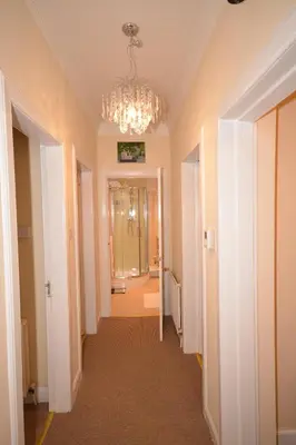 a hallway with a chandelier and a hallway with a bathroom at Wallace Apartment in Stirling