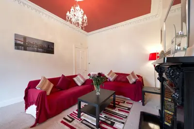 a living room with a red couch and a table at Wallace Apartment in Stirling