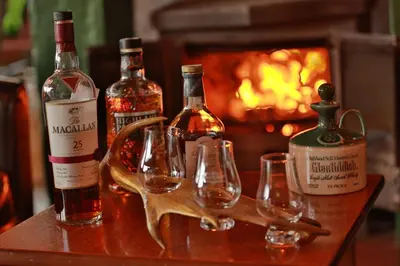 a group of wine bottles and glasses on a table with a fireplace at MacDonald Hotel & Cabins in Kinlochleven