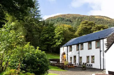 a white house with a mountain in the background at Argyll Barn in Colintraive