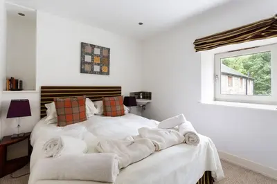 a white bedroom with a bed with towels on it at Argyll Barn in Colintraive