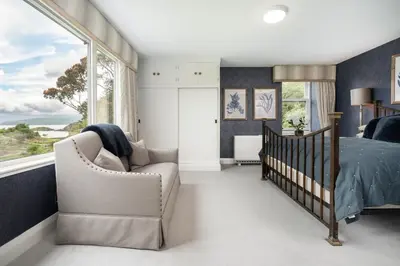 a bedroom with a bed and a chair and a window at Loch View House in Kilfinan