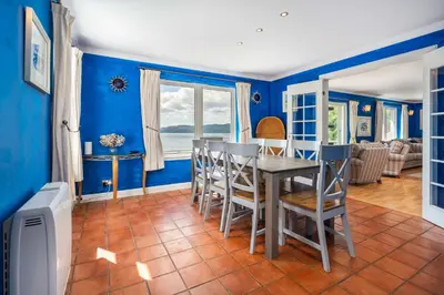 a dining room with blue walls and a table and chairs at Seal Bay Cottage in Kilfinan