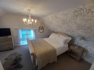 a bedroom with a large white bed and a chandelier at Beautiful Historic Cottage in Callander