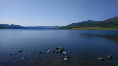 a large lake with rocks in the water at Beautiful Historic Cottage in Callander