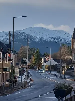 a street in a town with a snow covered mountain at Beautiful Historic Cottage in Callander