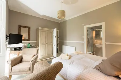 a bedroom with a bed and two chairs at Kilmaronock Manse B&B in Drymen