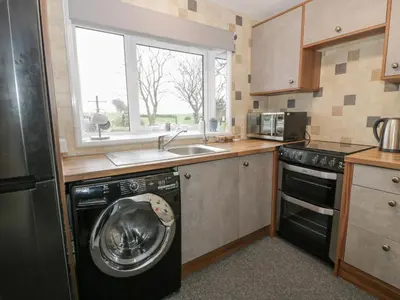 a kitchen with a washing machine and a sink at Rosalin Cottage in Irvine