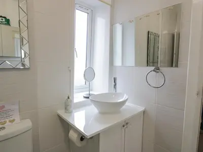 a white bathroom with a sink and a mirror at Rosalin Cottage in Irvine