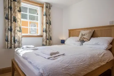 a bedroom with a bed with white sheets and a window at Luxury Flat, 20 Minutes by train from Edinburgh in Inverkeithing