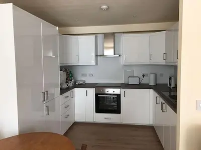 a white kitchen with white cabinets and a wooden floor at Luxury Flat, 20 Minutes by train from Edinburgh in Inverkeithing