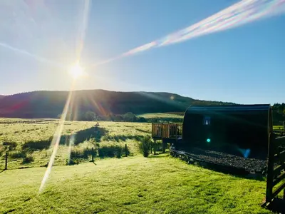 a train traveling through a field with the sun in the sky at The Pod Over By in Kilmichael Glassary