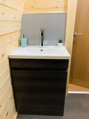 a bathroom with a white sink and a black cabinet at The Pod Over By in Kilmichael Glassary