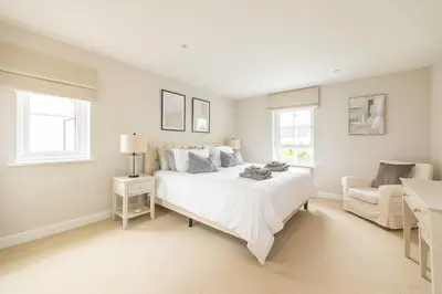 a white bedroom with a bed and a chair at Luxury Detached Home in Edinburgh