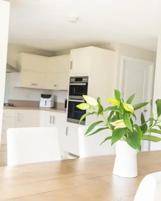 a white kitchen with a table with a plant on it at Luxury Detached Home in Edinburgh