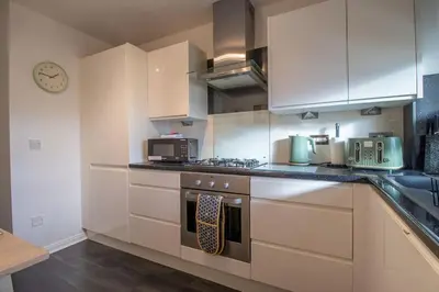 a kitchen with white cabinets and a stove top oven at Park View-modern 2 bed apartment in Motherwell