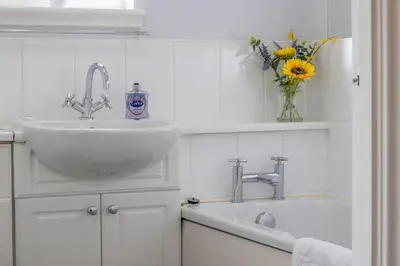 a bathroom with a sink and a vase of flowers at Park View-modern 2 bed apartment in Motherwell