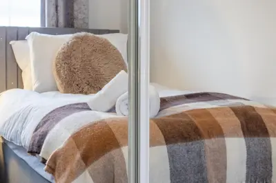 a bed with a brown and white blanket on it at Park View-modern 2 bed apartment in Motherwell