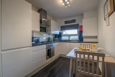 a kitchen with white cabinets and a table with drinks on it at Park View-modern 2 bed apartment in Motherwell