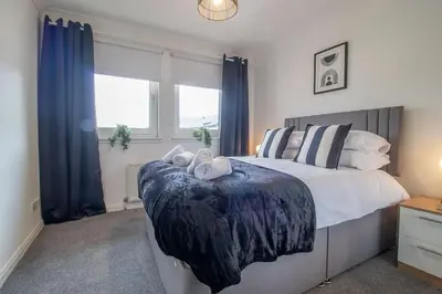 a bedroom with a bed with two towels on it at Park View-modern 2 bed apartment in Motherwell